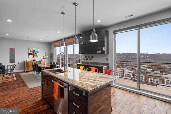 an open kitchen with granite countertop a stove dining table chairs and a view of living room