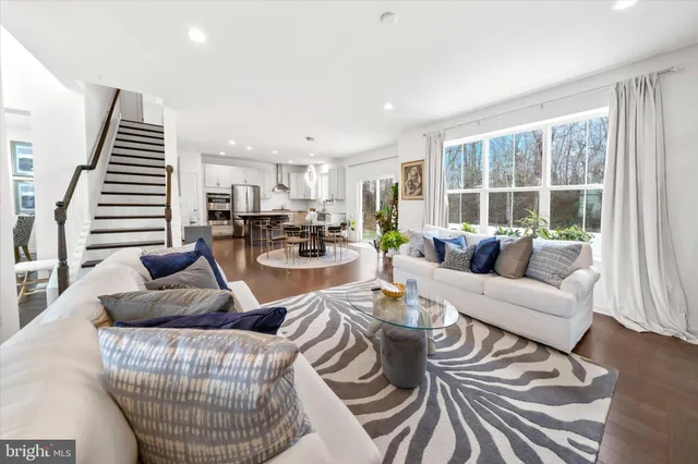 a living room with furniture and kitchen view with wooden floor