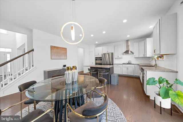 a large kitchen with stainless steel appliances granite countertop a stove a sink a refrigerator and white cabinets