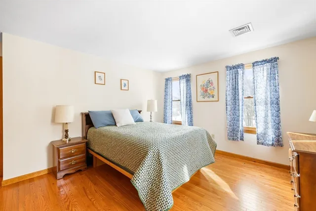a spacious bedroom with a bed and wooden floor