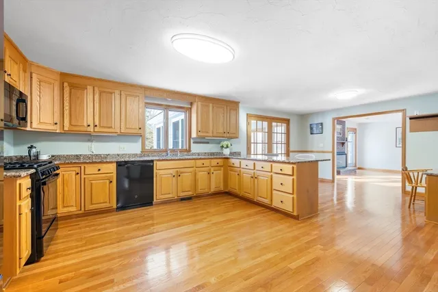 a large kitchen with stainless steel appliances granite countertop a stove cabinets and wooden floor