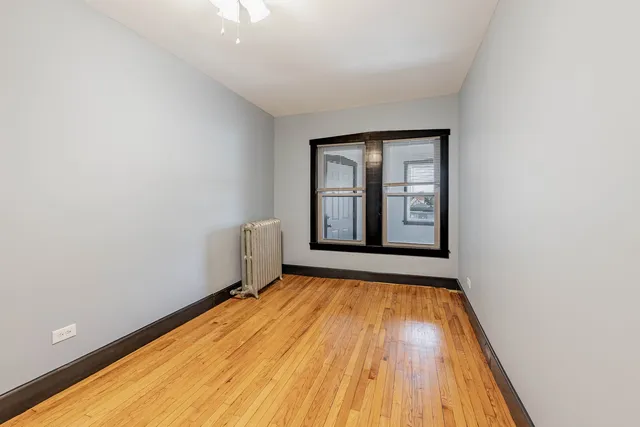a view of an empty room with window and wooden floor