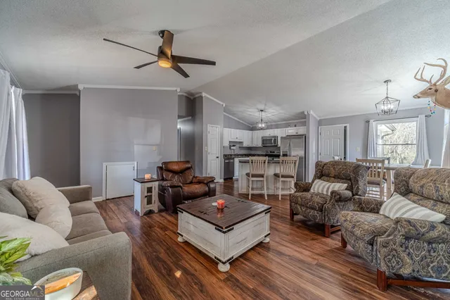 a living room with furniture kitchen view and a flat screen tv