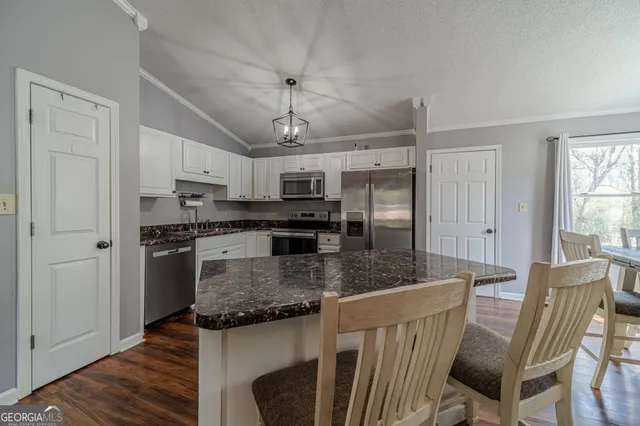 a kitchen with granite countertop white cabinets and stainless steel appliances