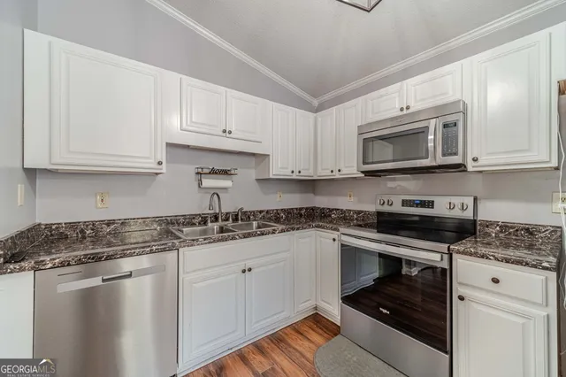 a kitchen with stainless steel appliances granite countertop a stove a sink dishwasher a refrigerator and a microwave oven with wooden floor