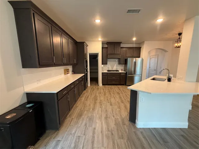 a large kitchen with a large counter top wooden cabinets and stainless steel appliances