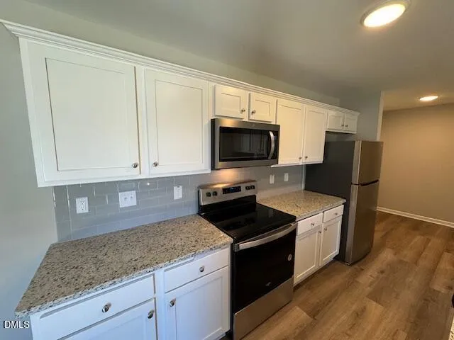 a kitchen with granite countertop white cabinets and black stainless steel appliances