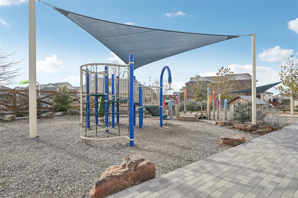 4430 Prairie Crossing Prosper, TX 75078 - Photo 4 of 15 Community playground area featuring a shade sail, various play structures, and a paved pathway