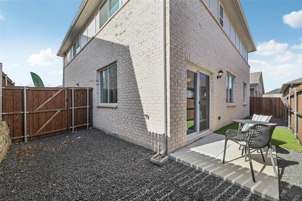 4430 Prairie Crossing Prosper, TX 75078 - Photo 9 of 15 The property features a brick exterior, a paved patio area, and a fenced yard with both gravel and artificial turf landscaping