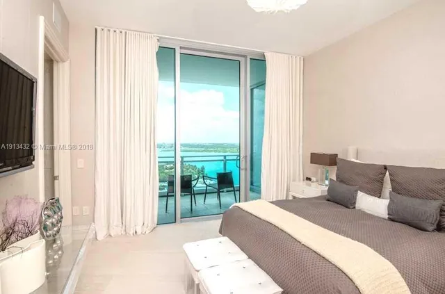 a bedroom with a large bed and a flat tv screen next to a window