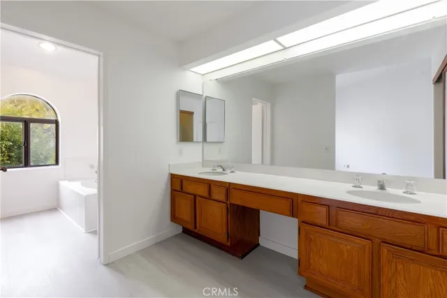a spacious bathroom with a double vanity sink a large mirror and a bathtub