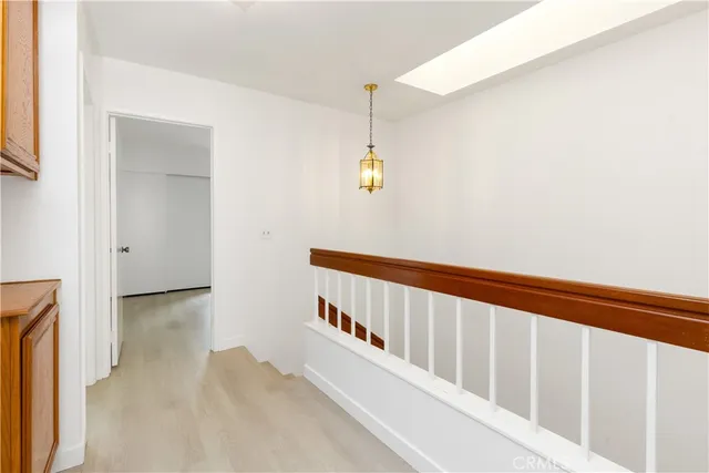a view of a hallway with wooden floor and a bathroom