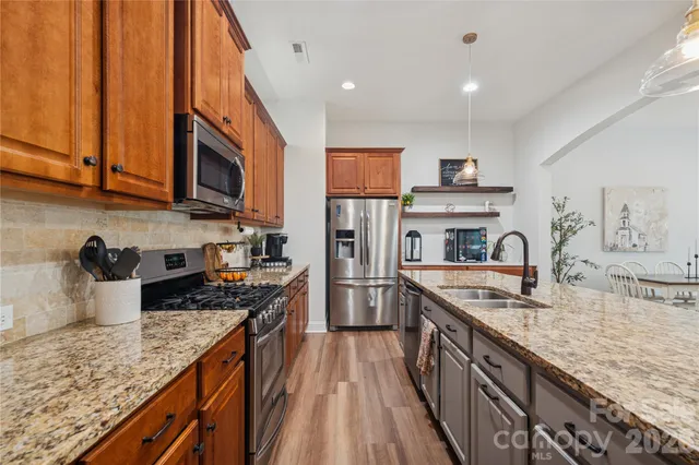a kitchen with granite countertop a sink a counter space appliances and cabinets
