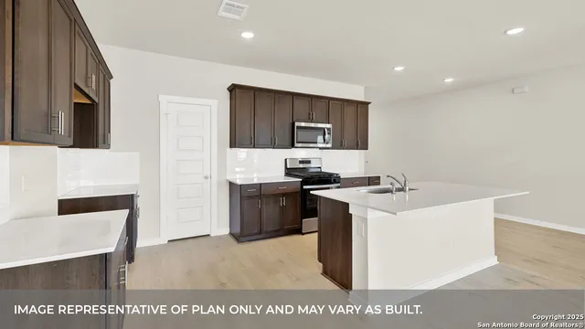 a kitchen with a sink a stove a refrigerator cabinets and a dining table