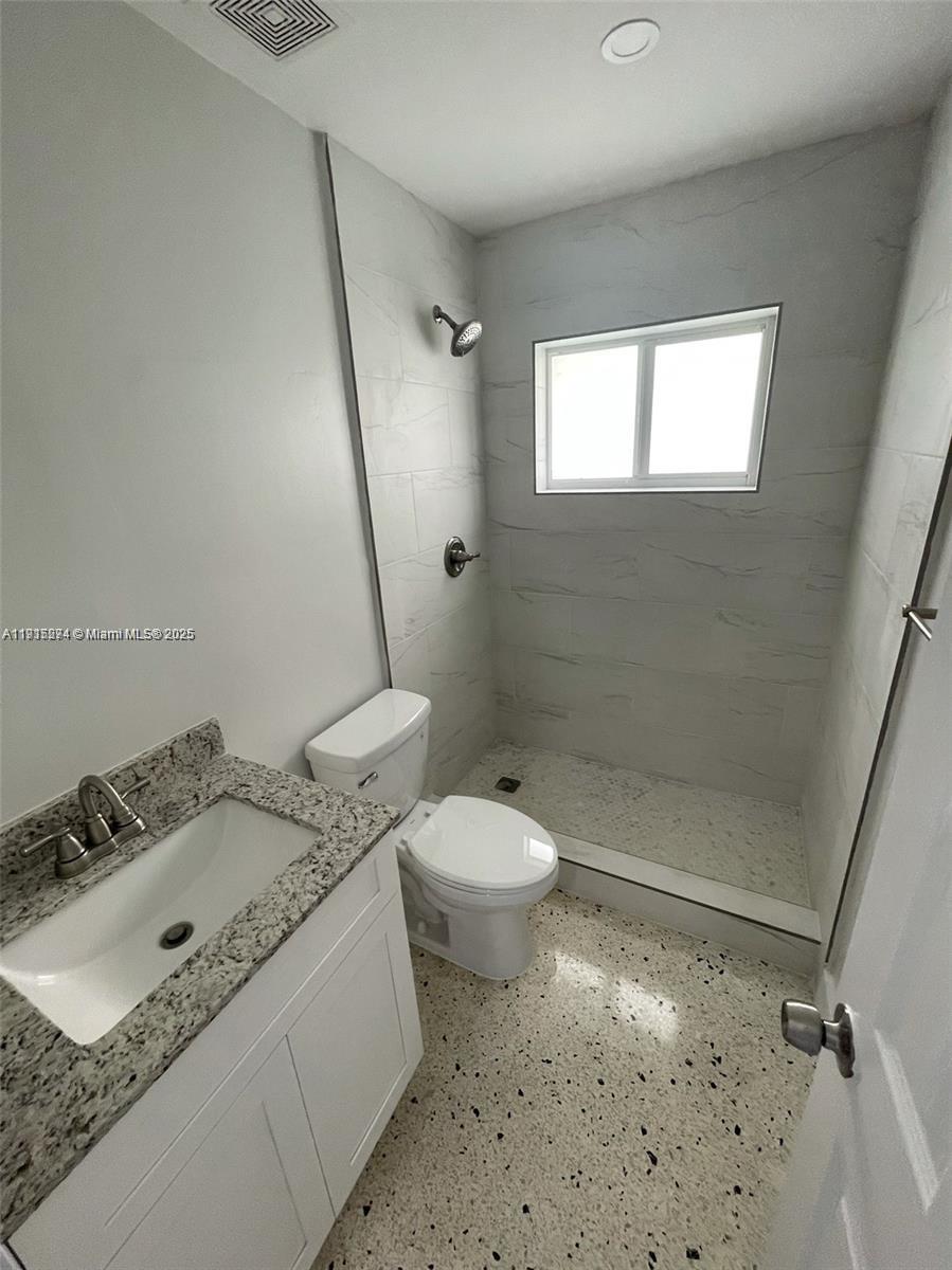 3518 Southwest 24th Terrace, Unit 3518 Miami, FL 33145 - Photo 10 of 11 a bathroom with a granite countertop sink a toilet and shower