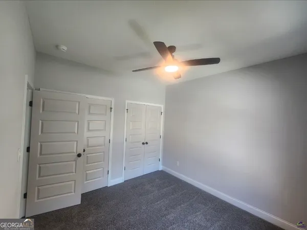 an empty room with closet and a ceiling fan