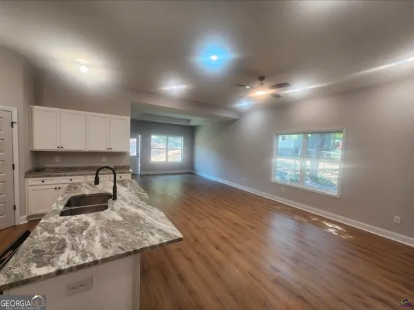 a kitchen with kitchen island granite countertop a stove and a wooden floors