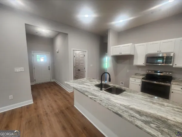 a kitchen with granite countertop a sink and a stove top oven