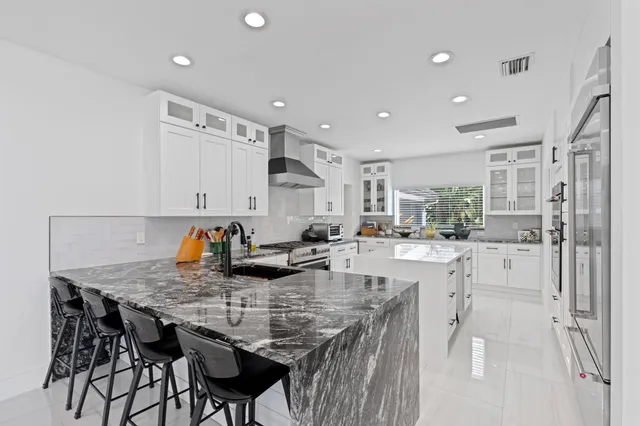 a kitchen with granite countertop a table chairs stove and white cabinets
