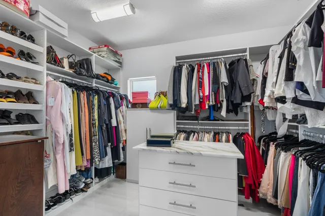 a view of walk in closet with clothes and shoes