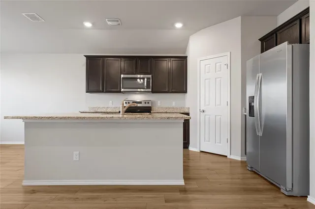 a view of kitchen with refrigerator stove and wooden floor
