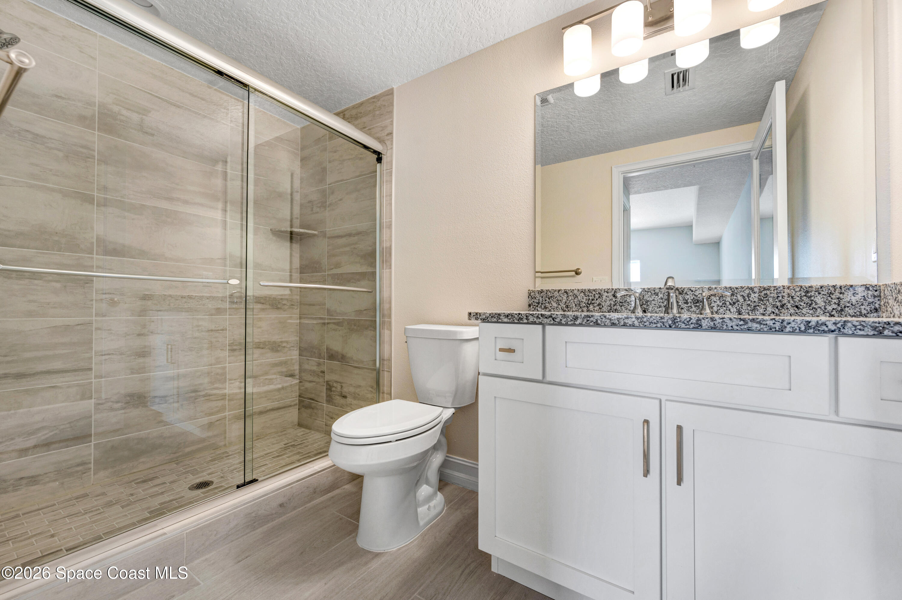 1805 Riverside Drive, Unit 304 Titusville, FL 32780 - Photo 18 of 46 a bathroom with a granite countertop sink toilet a mirror and shower