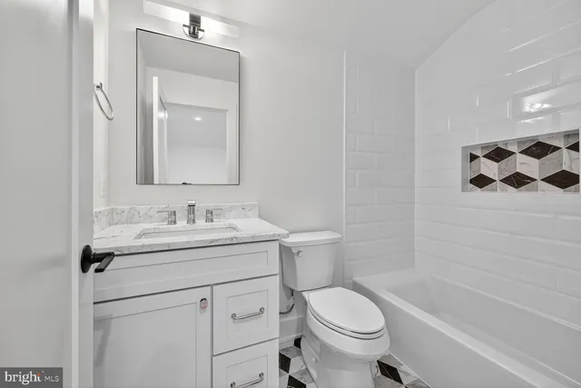 a bathroom with a granite countertop sink toilet mirror and shower