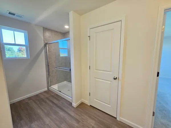 an empty room with wooden floor cabinet and windows