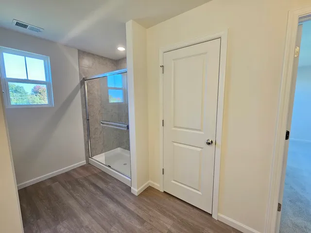 an empty room with wooden floor cabinet and windows