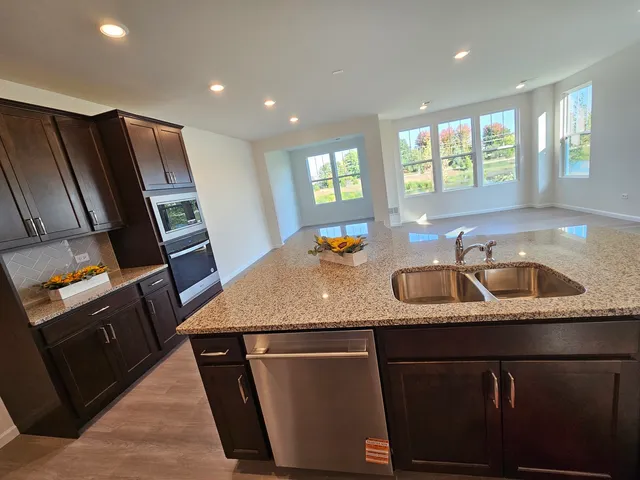 a kitchen with stainless steel appliances granite countertop a sink dishwasher a refrigerator and a stove