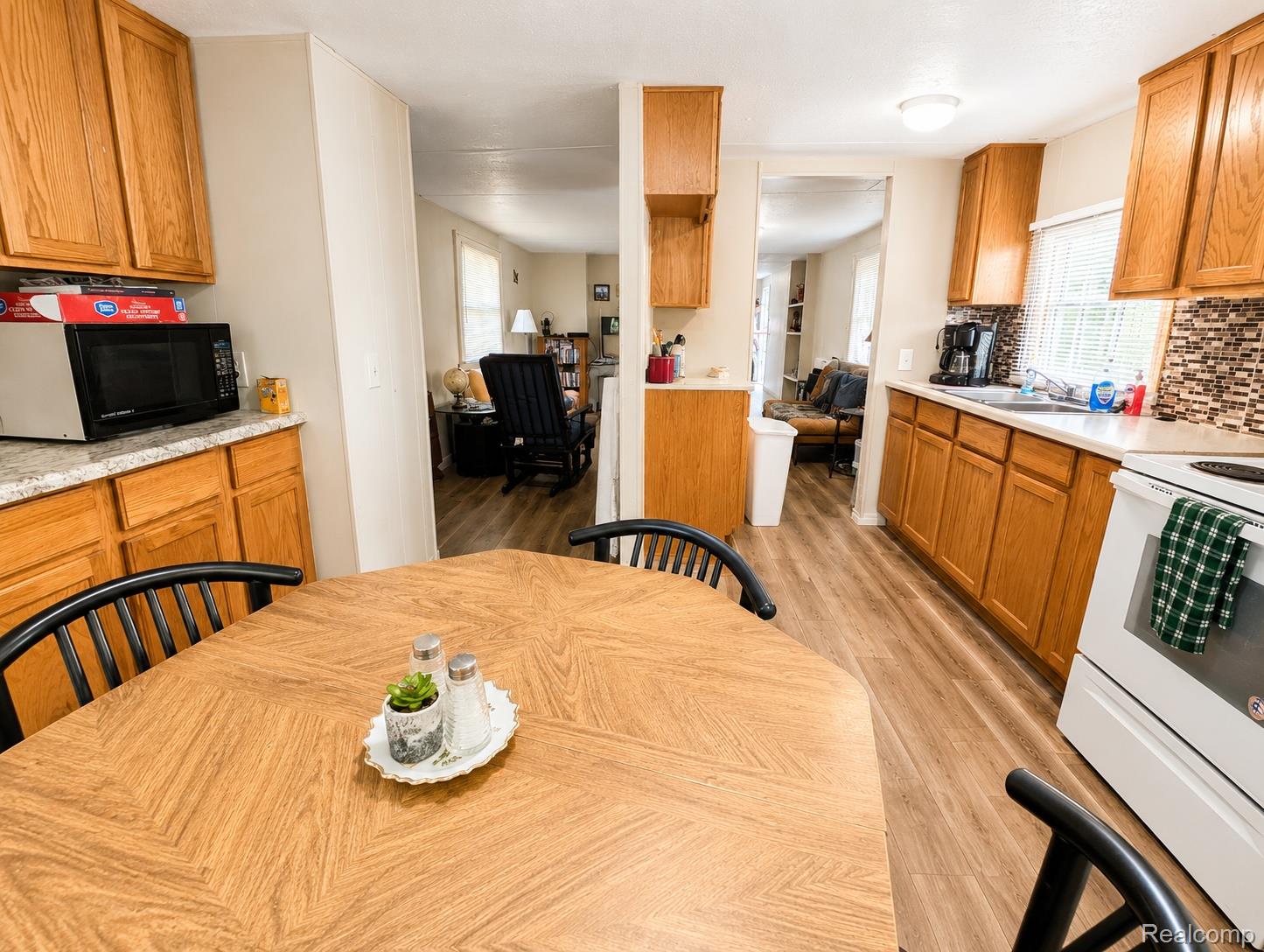 643 North Hockaday Road Gladwin, MI 48624 - Photo 5 of 24 Kitchen featuring wood-finish flooring, wood cabinetry, granite-look countertops, and a tiled backsplash