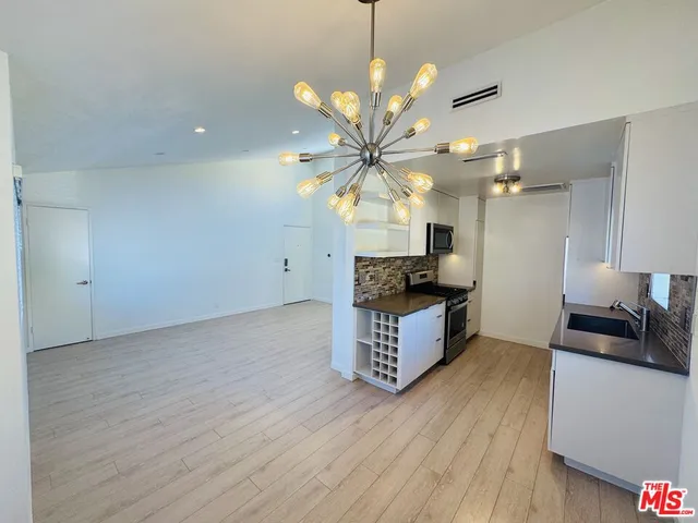 a kitchen with stainless steel appliances kitchen island wooden floors and view living room