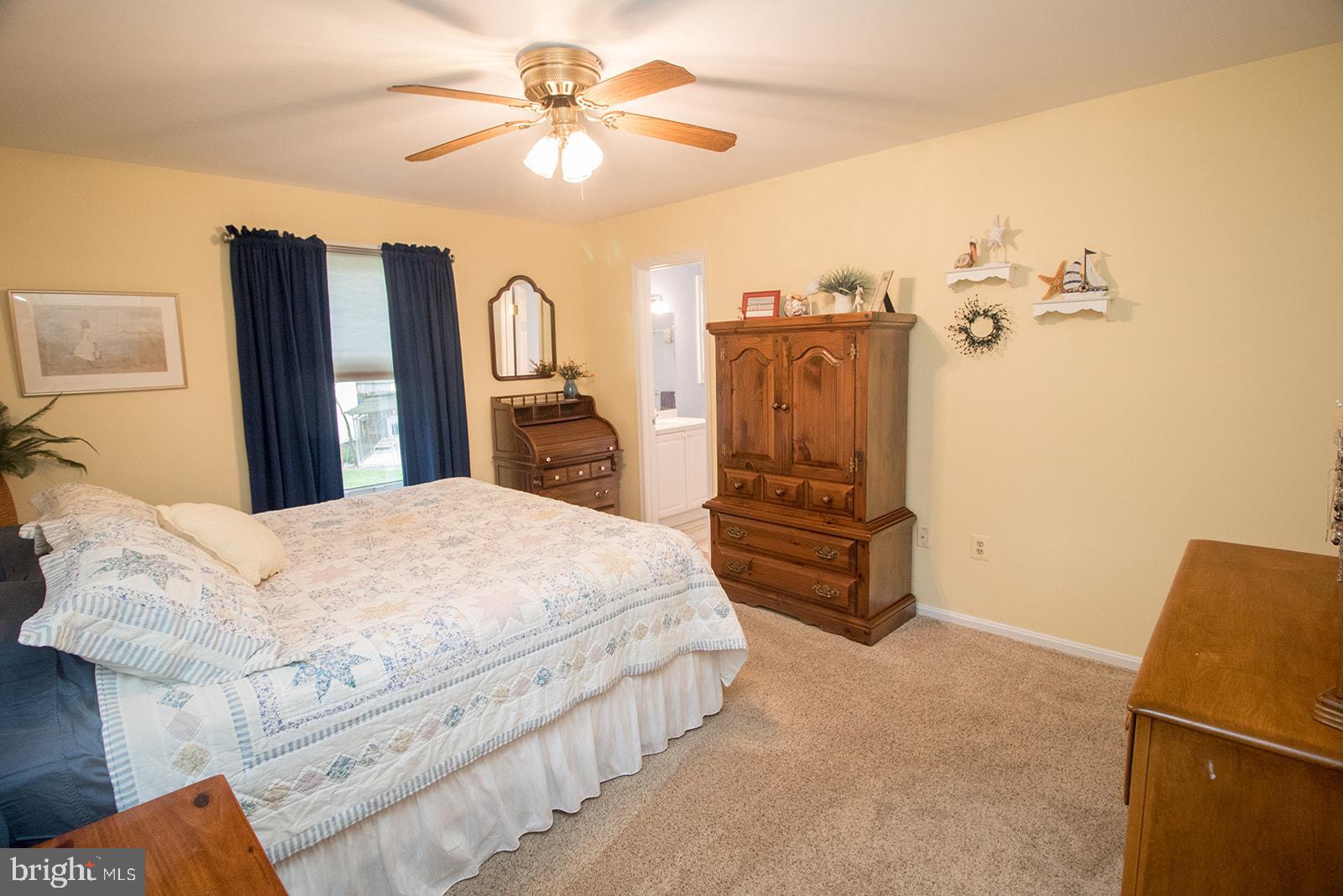 11620 Big Sandy Run Road Lusby, MD 20657 - Photo 18 of 64 a spacious bedroom with a bed a dresser and a chandelier
