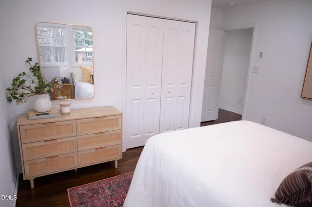 a bedroom with a bed table closet and mirror
