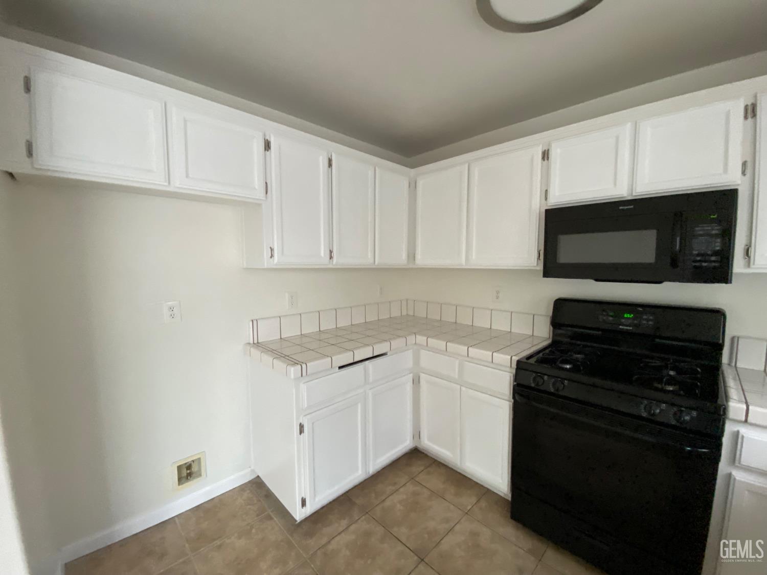 Undisclosed Address Bakersfield, CA 93307 - Photo 12 of 34 a kitchen with white cabinets and black appliances