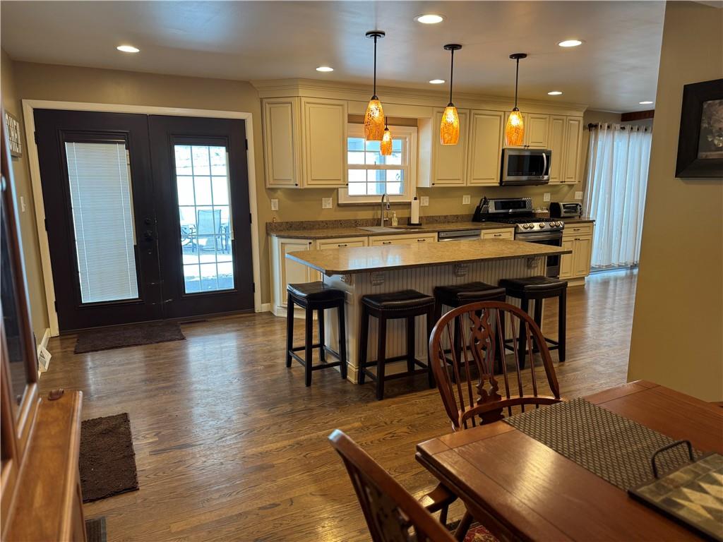 2072 Boyd School Road Wampum, PA 16157 - Photo 8 of 45 a kitchen with stainless steel appliances granite countertop a stove a refrigerator a kitchen island a dining table and chairs with wooden floor