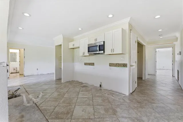 a view of an empty room with a window and a chandelier fan