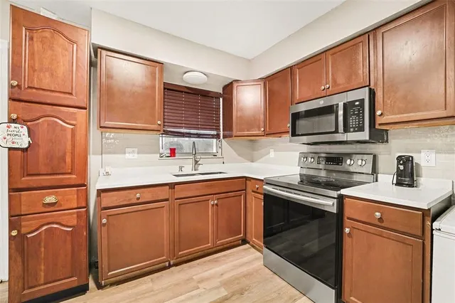 a kitchen with stainless steel appliances granite countertop a sink stove refrigerator and cabinets