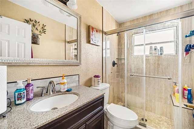 a bathroom with a granite countertop sink toilet and shower