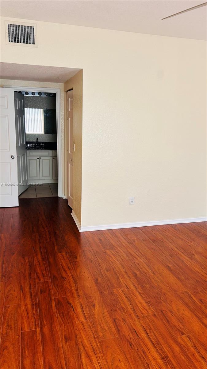 6732 West Sample Road, Unit 6732 Coral Springs, FL 33067 - Photo 16 of 25 a view of an empty room with wooden floor and a kitchen