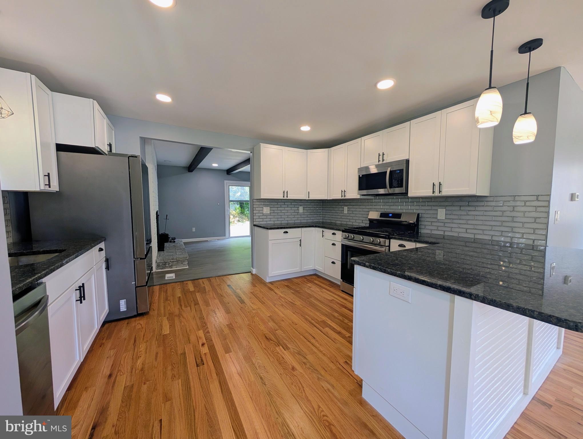 1037 Queens Road Vineland, NJ 08361 - Photo 21 of 40 a kitchen with stainless steel appliances a stove top oven a sink a refrigerator white cabinets and wooden floor