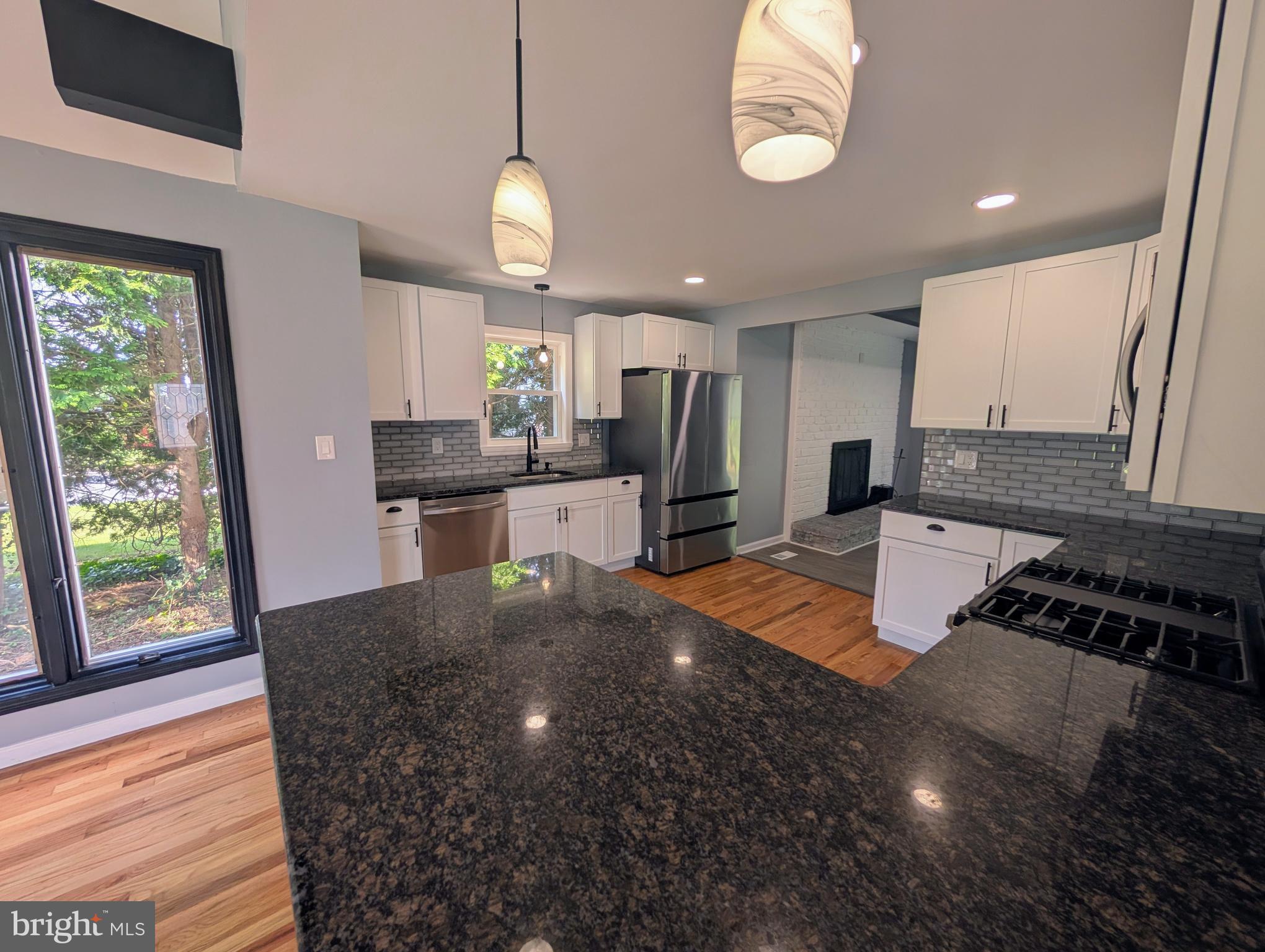 1037 Queens Road Vineland, NJ 08361 - Photo 22 of 40 a kitchen with stainless steel appliances granite countertop a sink a stove white cabinets a dining table and chairs with wooden floor