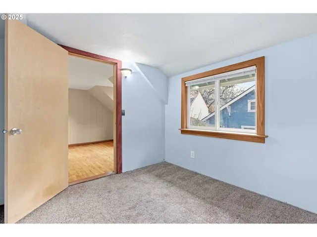 view of an empty room with wooden floor and a bathroom