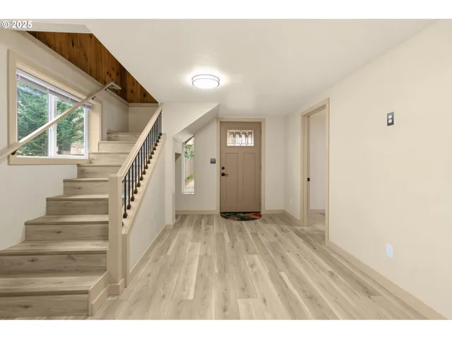 a view of an empty room with wooden floor and stairs