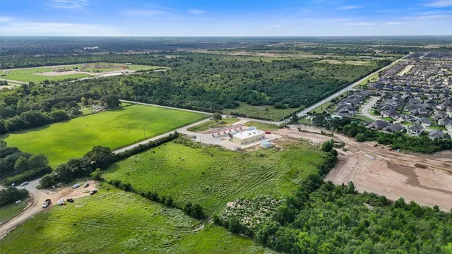 an aerial view of a residential houses with outdoor space and trees