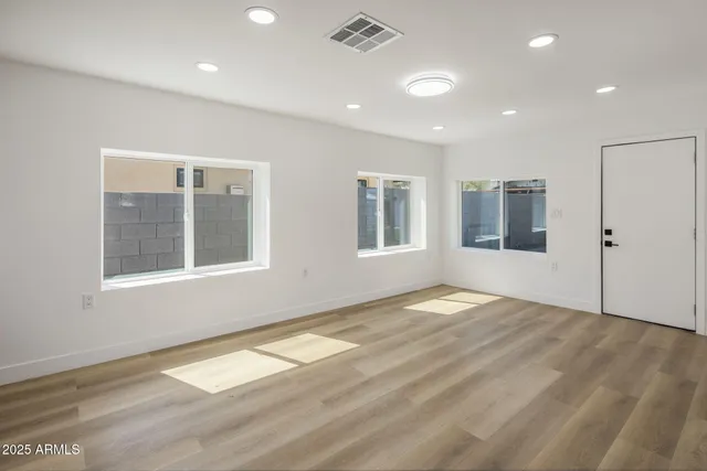a view of empty room with wooden floor and fan