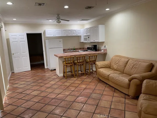 a living room with stainless steel appliances furniture a sink and a refrigerator