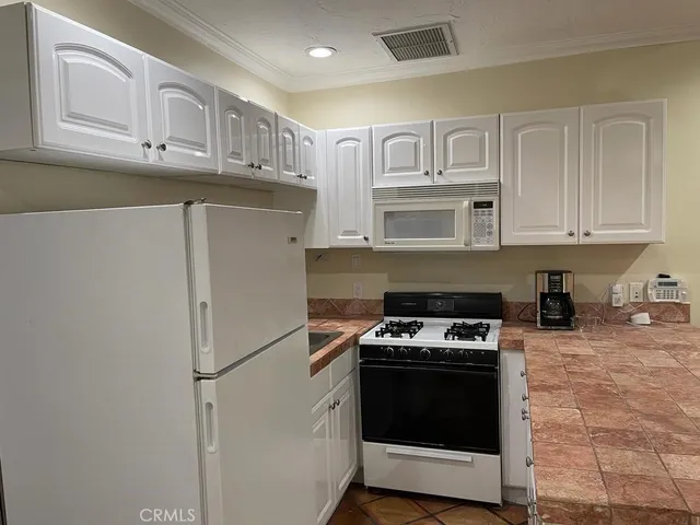a kitchen with stainless steel appliances granite countertop white cabinets and a stove a refrigerator a oven with white cabinets