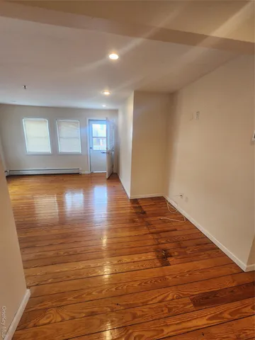 a view of empty room with wooden floor and window