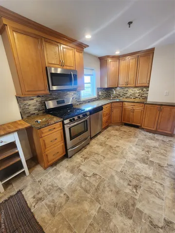 a kitchen with stainless steel appliances granite countertop a stove a sink and a refrigerator